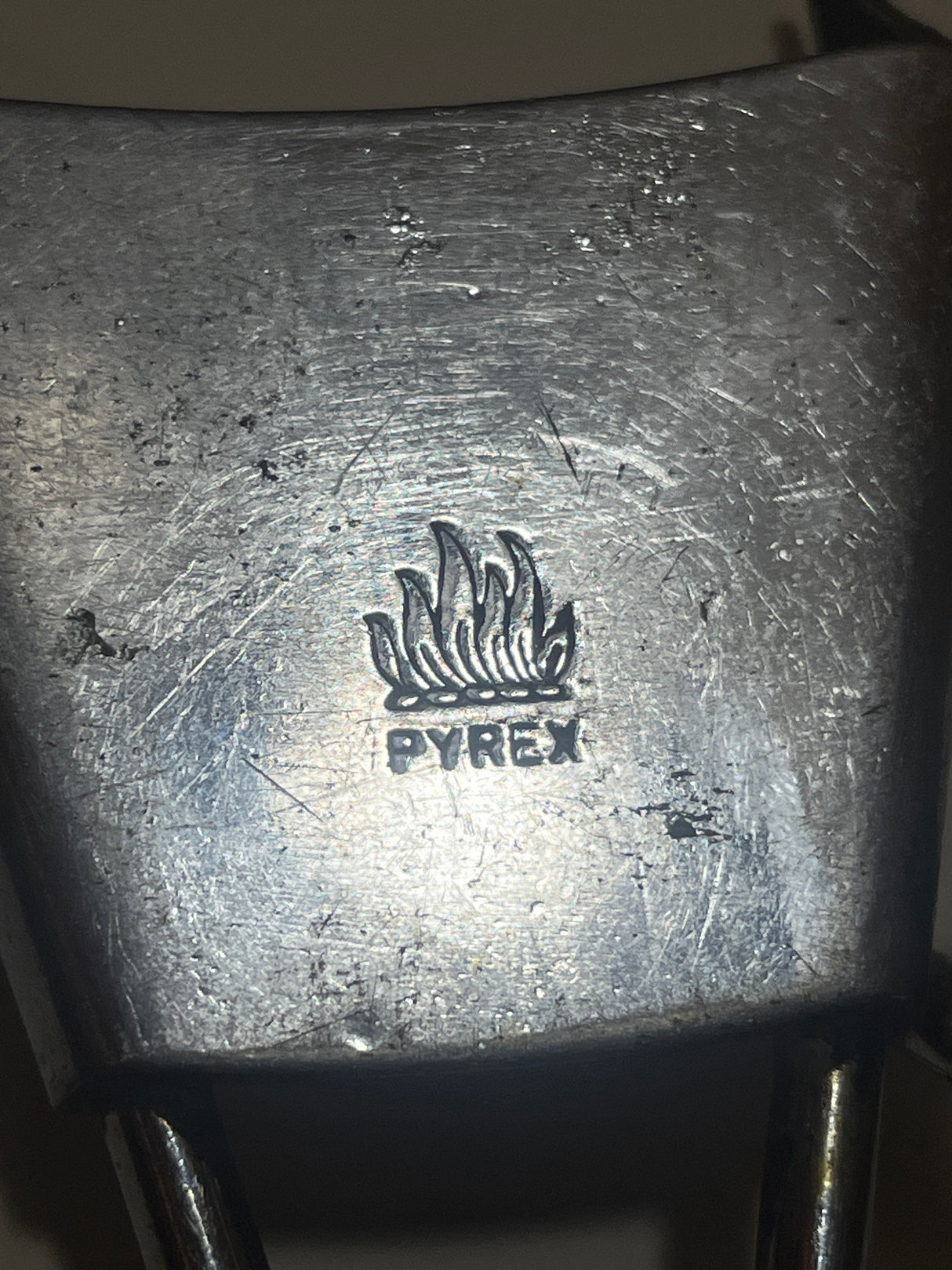 PYREX Flameware removable skillet handle, featuring a stamped Pyrex logo and flame, with dual metal prongs, designed for secure attachment to cookware.