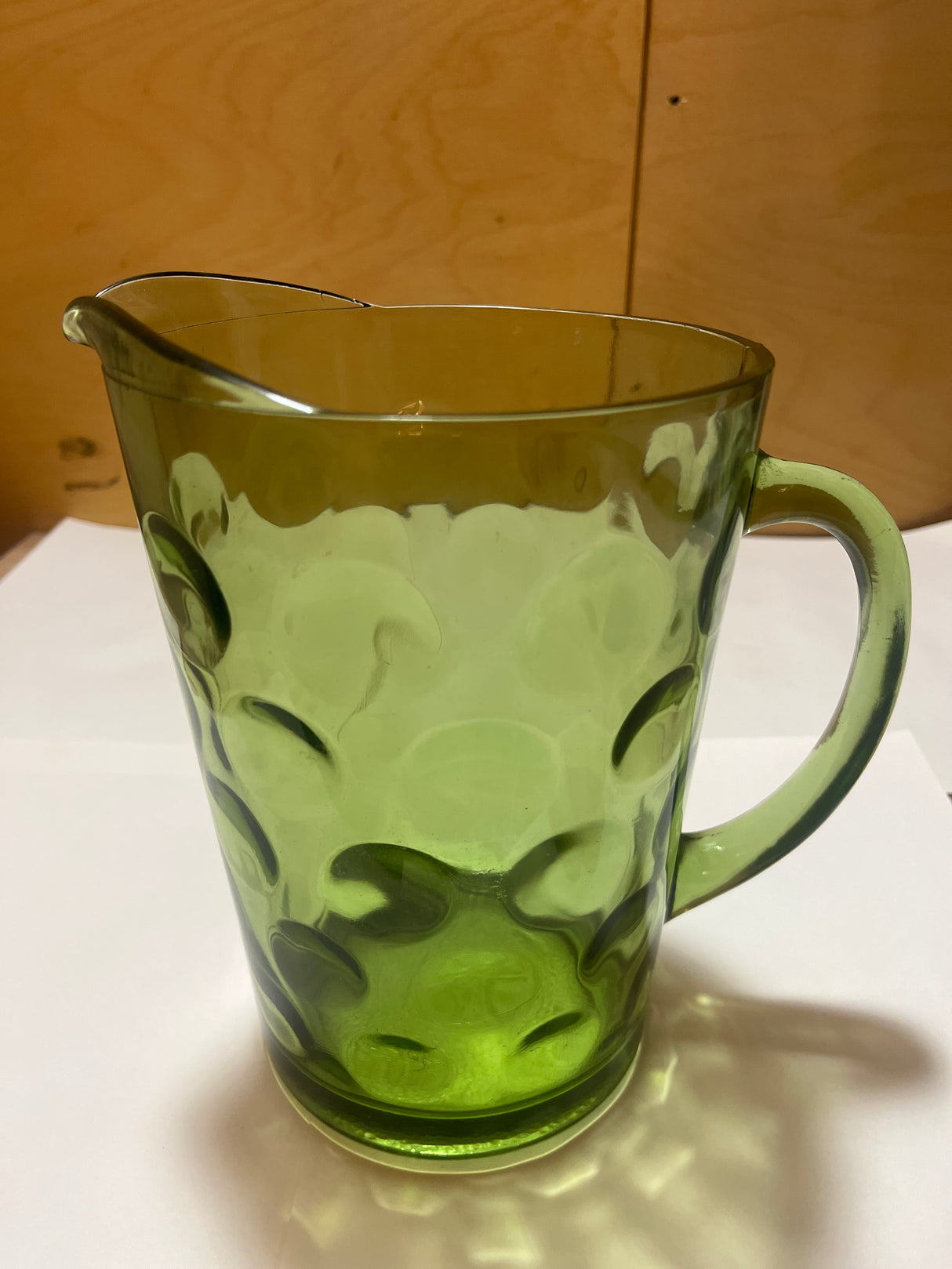 Hazel Atlas Eldorado avocado green coin dot glass pitcher with a translucent body, single handle, and small spout, featuring a raised circular pattern against a white surface.