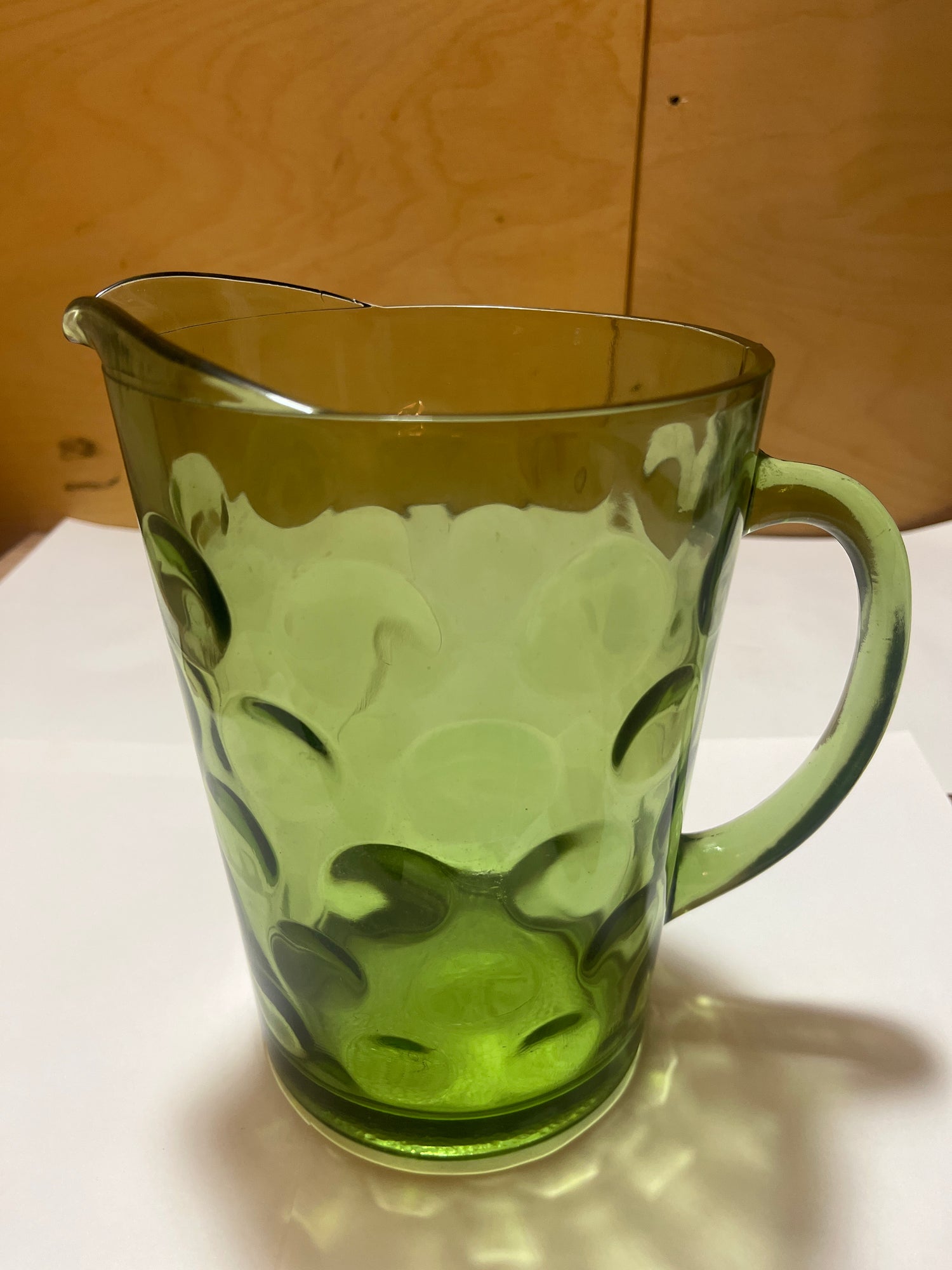 Hazel Atlas Eldorado avocado green coin dot glass pitcher with a translucent body, single handle, and small spout, featuring a raised circular pattern against a white surface.