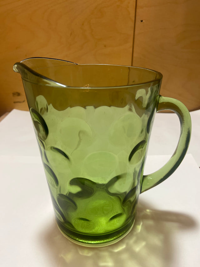 Hazel Atlas Eldorado avocado green coin dot glass pitcher with a translucent body, single handle, and small spout, featuring a raised circular pattern against a white surface.