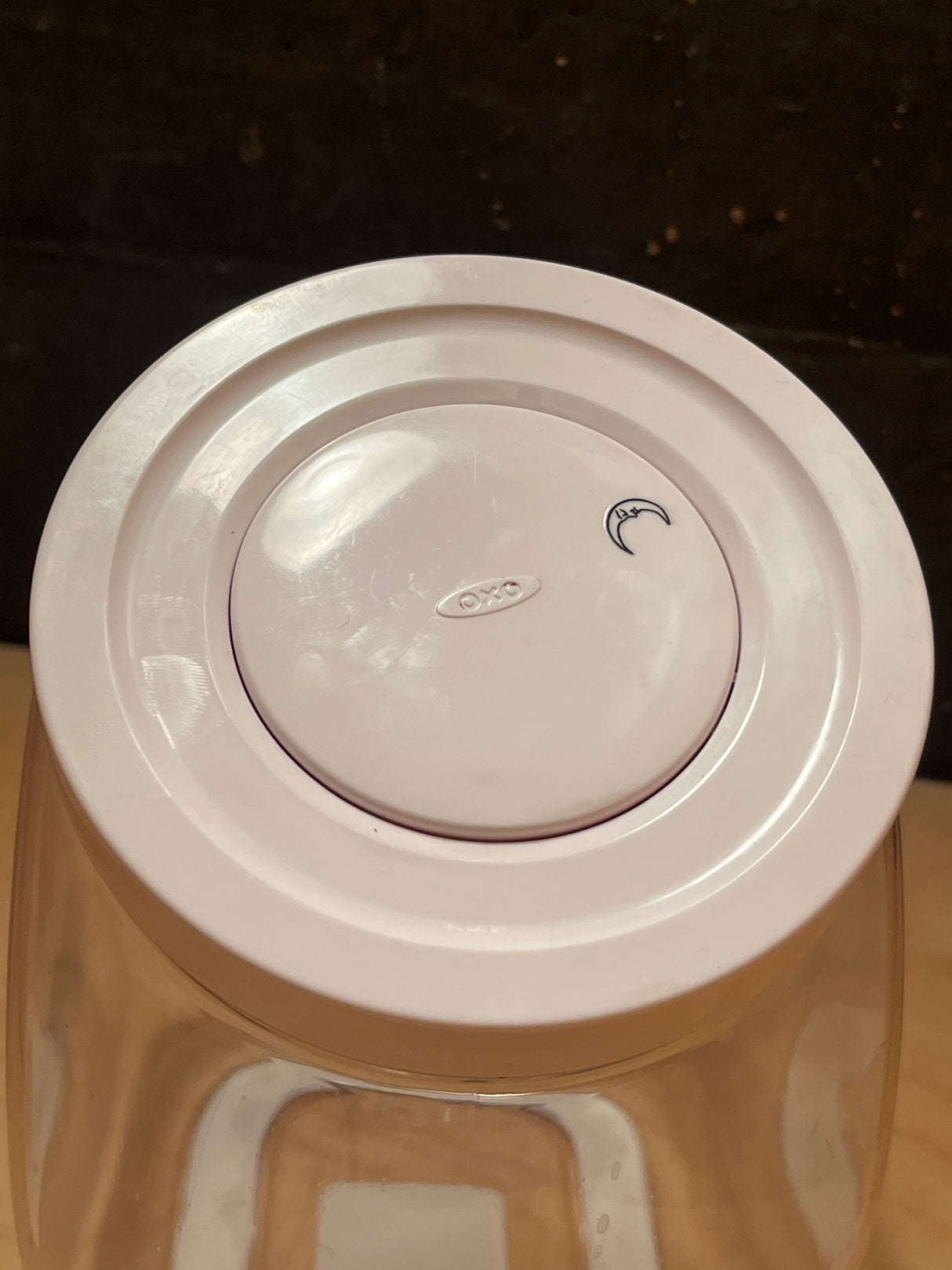 Top view of OXO POP medium food storage jar 3 qt. featuring a white lid with a round silicone seal, embossed OXO button, and a crescent-moon doodle.