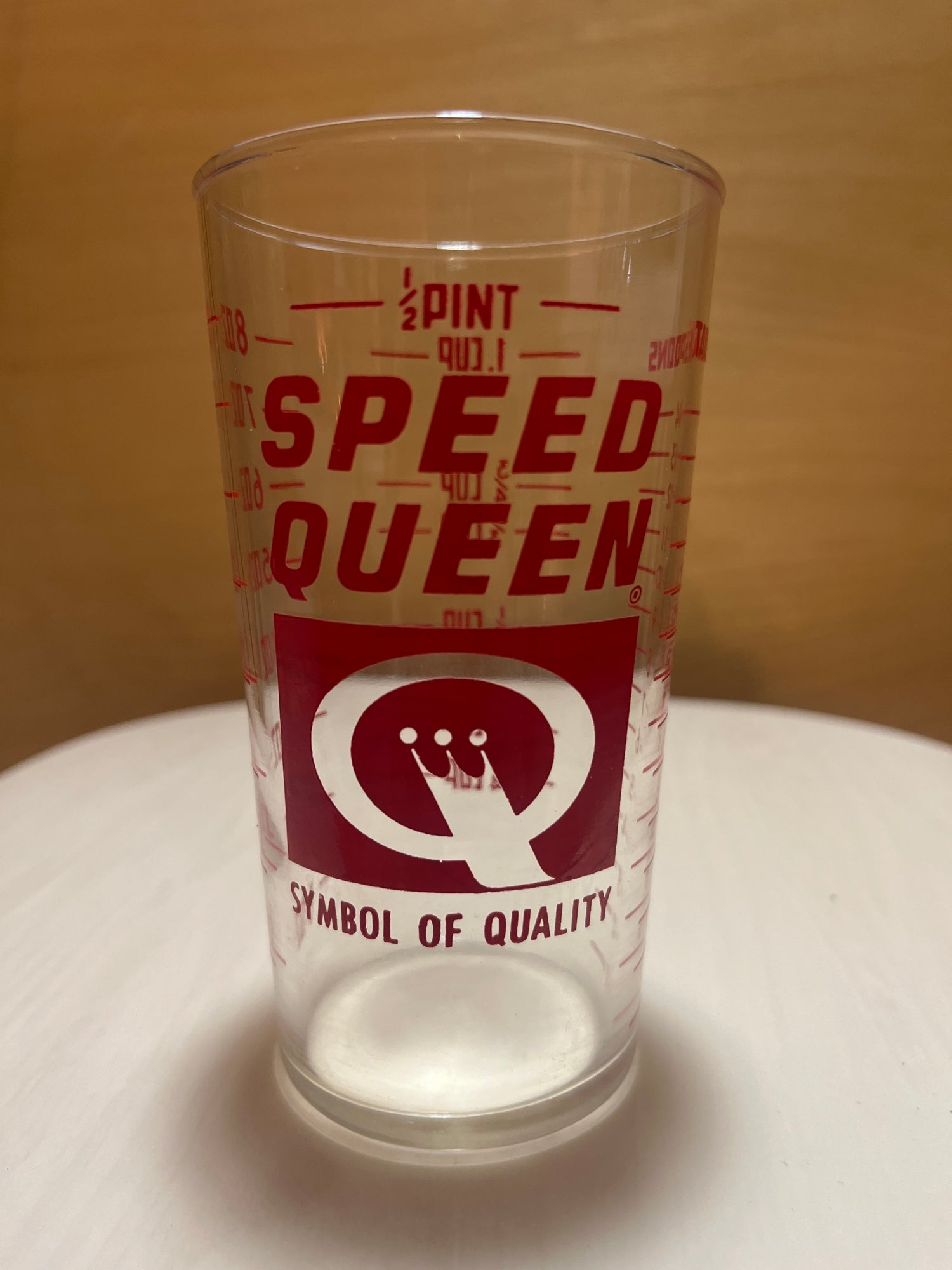 Speed Queen glass measuring cup with a ½-pint capacity, featuring red SPEED QUEEN branding, a stylized Q logo, SYMBOL OF QUALITY tagline, and fluid ounce markings.