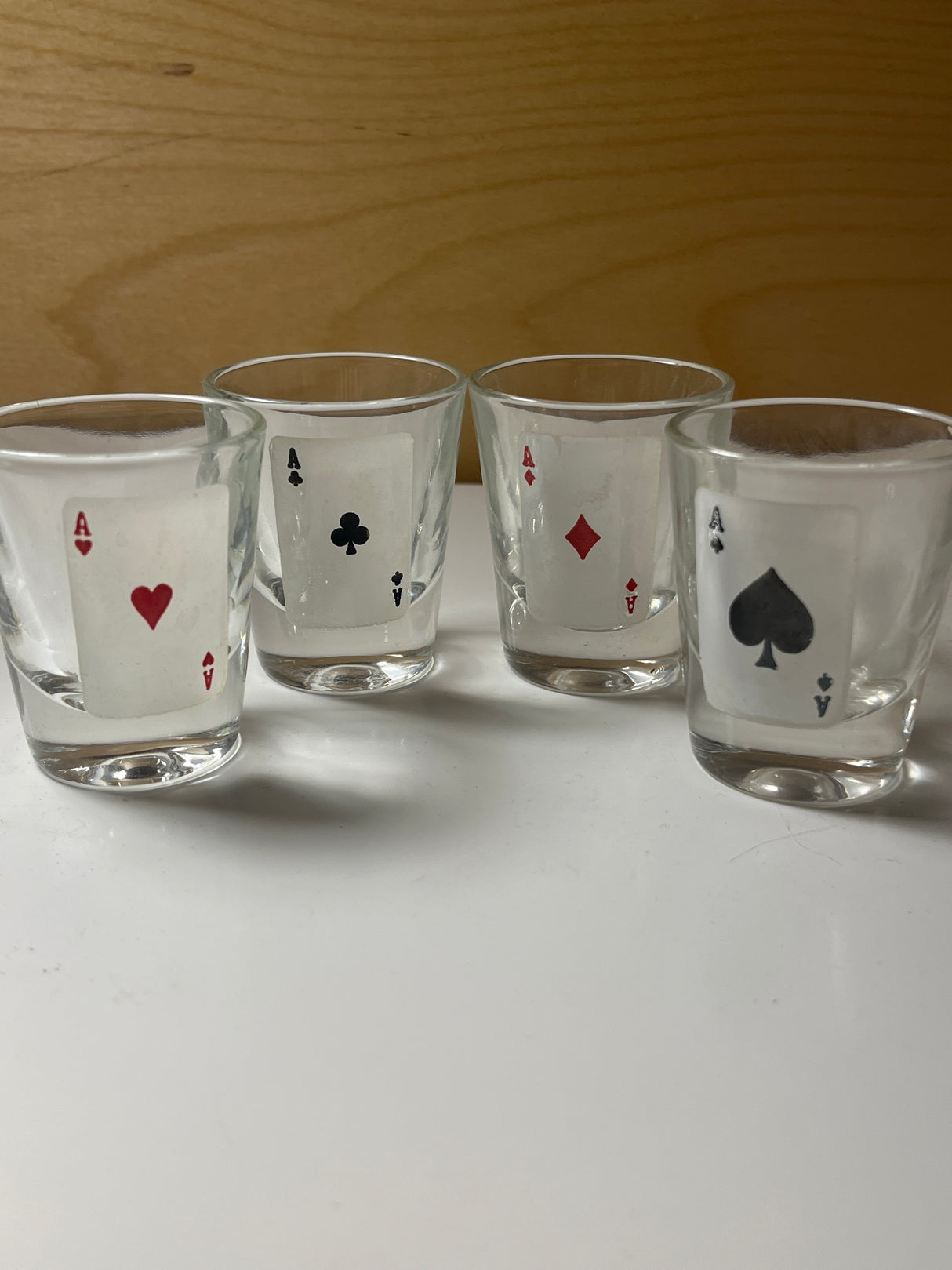 RARE 1960’s MCM poker-themed drinkware set featuring four clear shot glasses, each adorned with a distinct ace card design in a row.