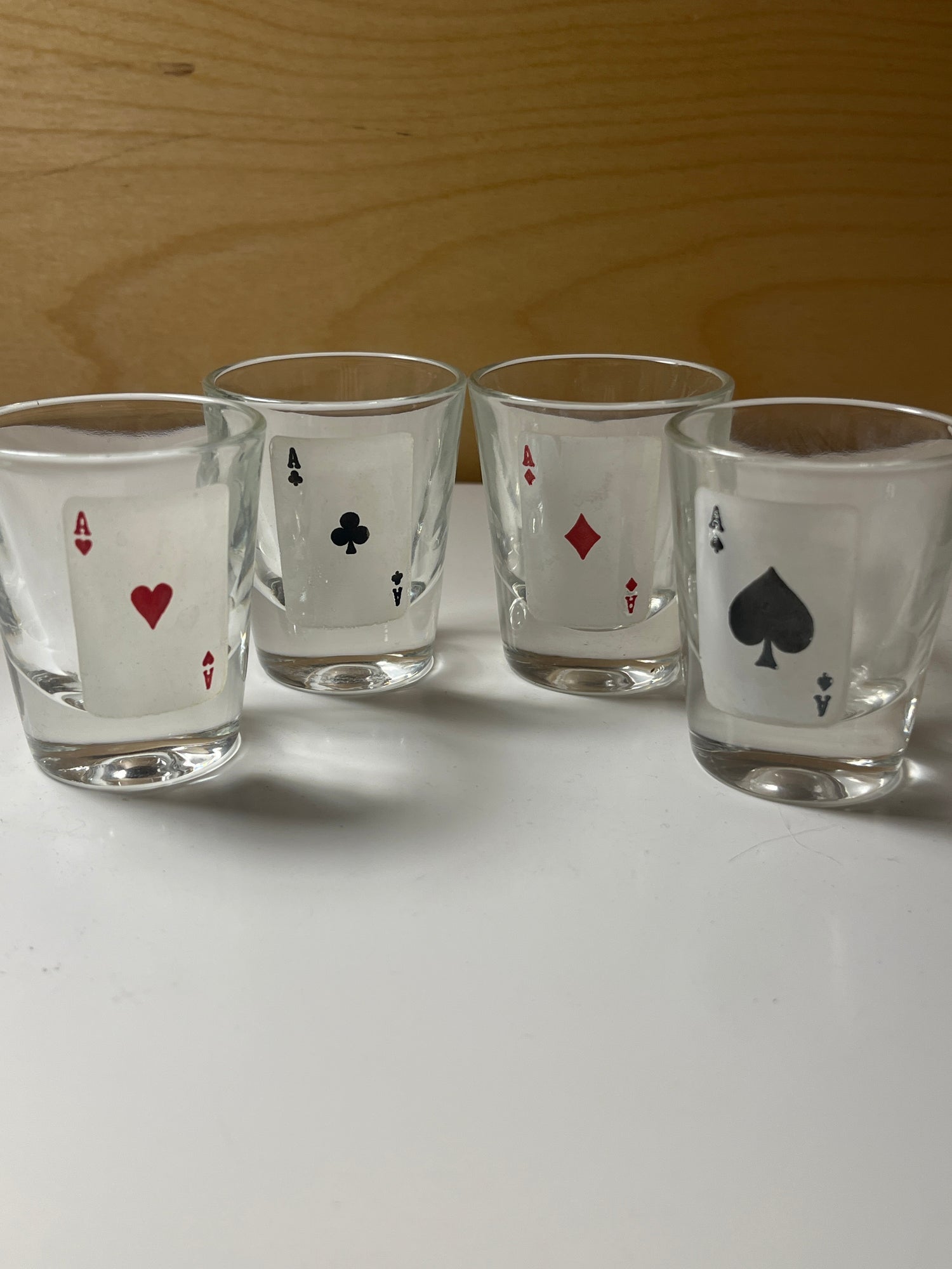RARE 1960’s MCM poker-themed drinkware set featuring four clear shot glasses, each adorned with a distinct ace card design in a row.