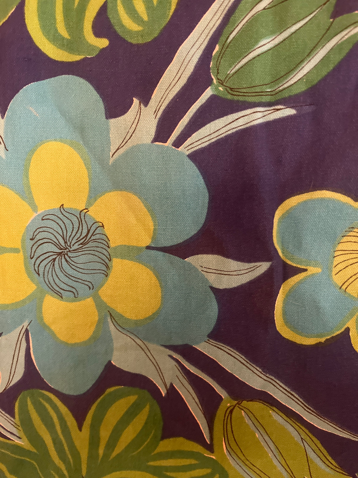 Vintage tablecloth featuring bold, stylized floral patterns with large flowers and green leaves in a detailed, intricate design.