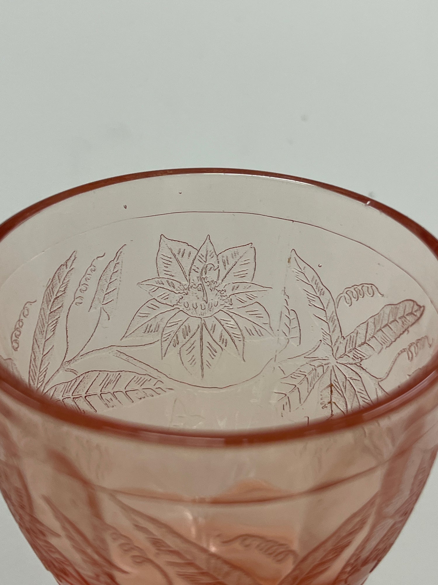 RARE Jeanette Depression glass pink floral poinsettia candy jar with lid, featuring ornate flower and leaf designs, and a faceted, footed bottom.