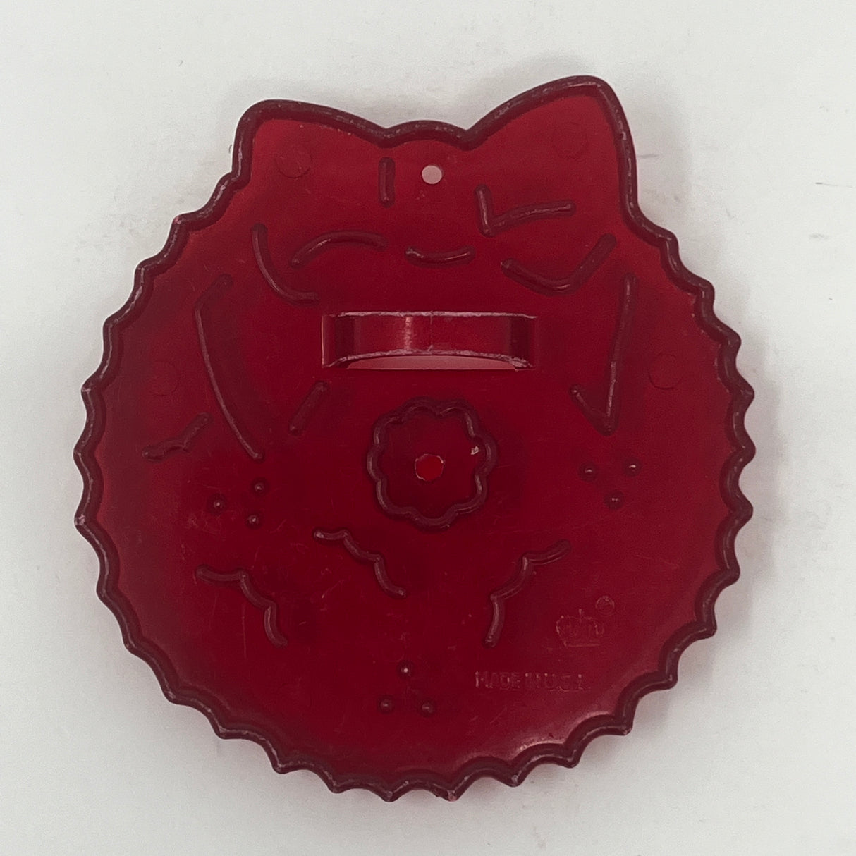 Red plastic mid century cookie cutters, one with a cat face, another with a flower shape, and a white line design.