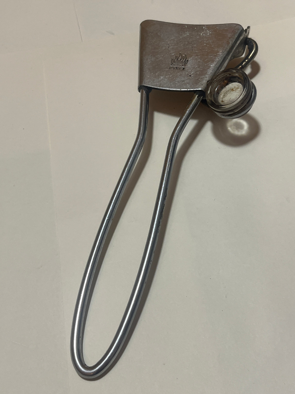 PYREX Flameware removable skillet handle, shown as stainless steel tongs with a spring-loaded clamping jaw, designed for handling hot glass beakers or flasks.