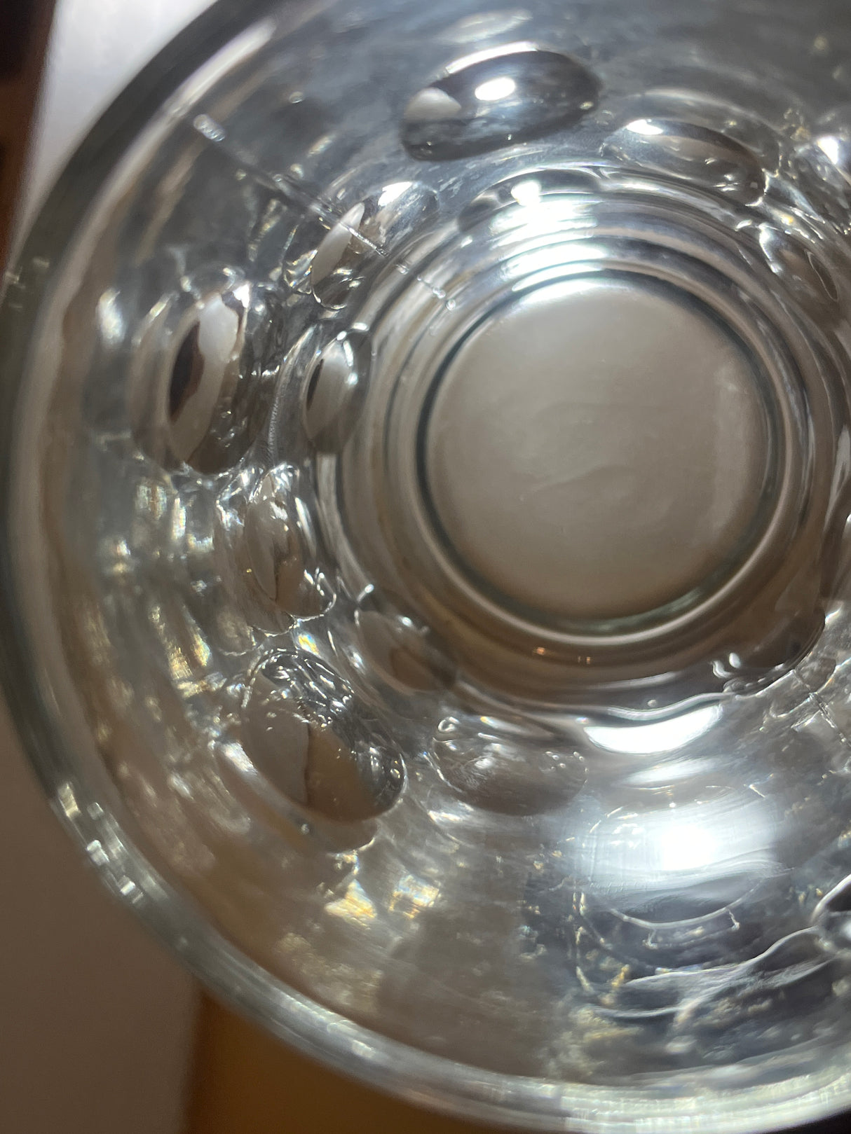Top-down view of Anchor Hocking vintage clear thumbprint dimple glass mug, showing water with droplets and bubbles clinging to the interior.