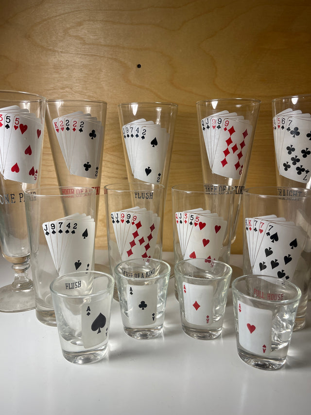 RARE 1960’s MCM poker-themed drinkware set featuring tall and shot glasses, each displaying unique five-card poker hands like Full House and Straight.