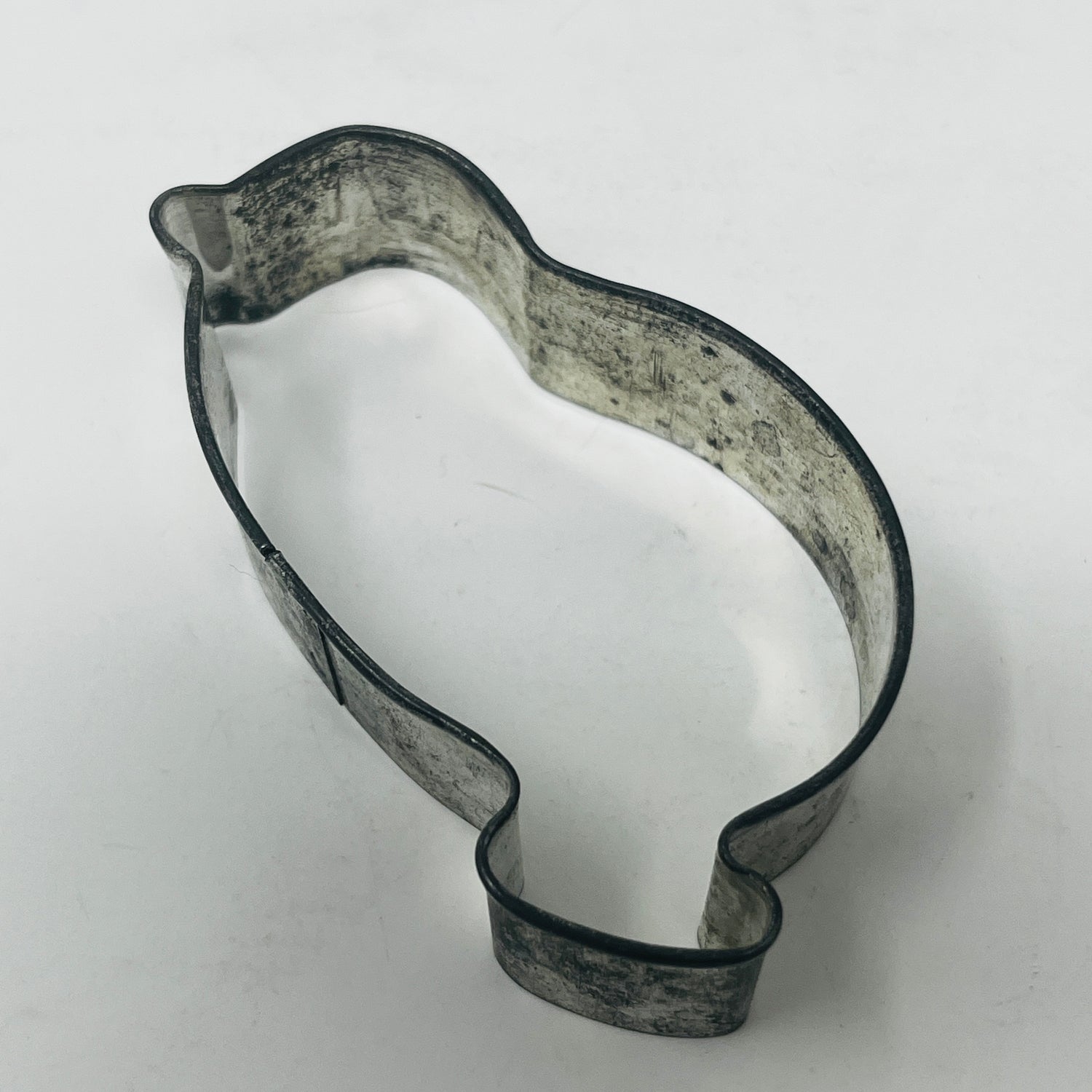 Mid-century metal cookie cutter shaped like a penguin, featuring a large, easy-to-grip handle, part of a unique collection of adaptive cookie cutter shapes.