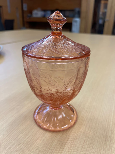RARE Jeanette Depression glass pink floral poinsettia candy jar with lid, showcasing ornate floral patterns and a faceted footed bottom, highlighting vintage elegance.