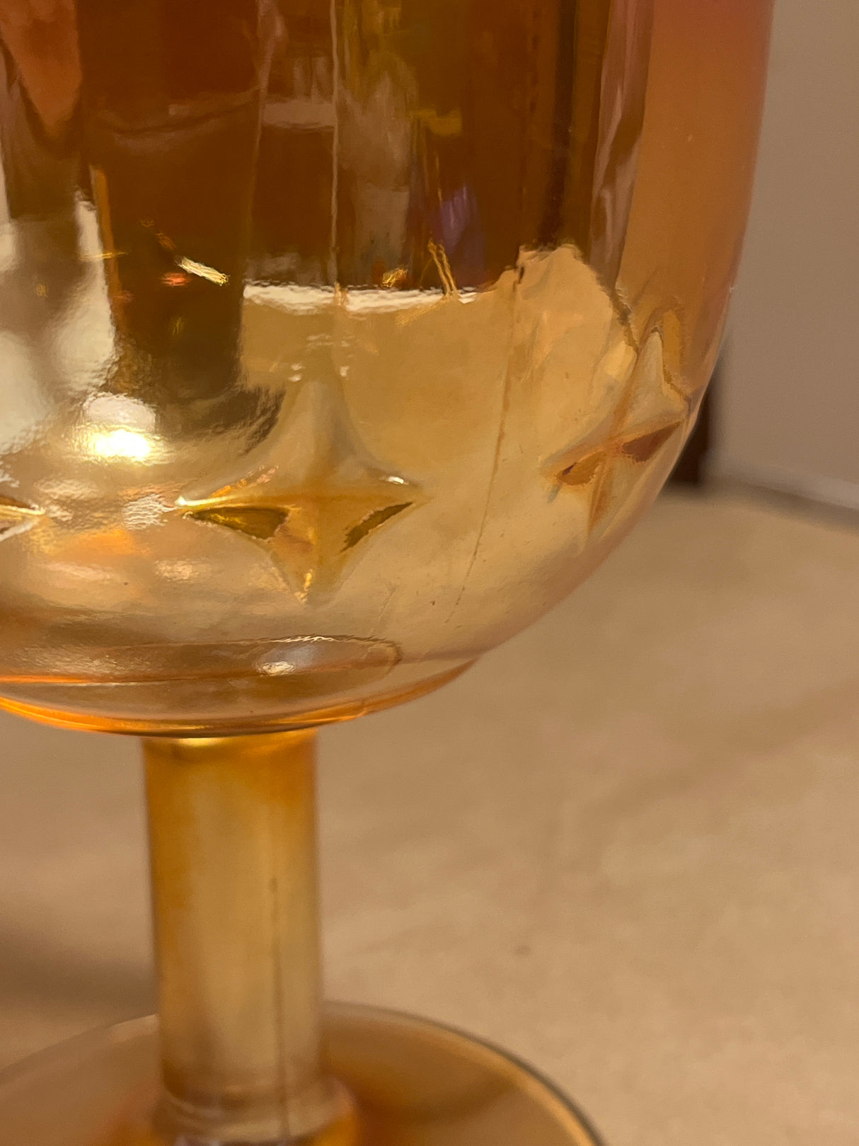 Bartlett Collins Star Marigold Carnival orange glass water goblet with a stem, featuring a raised star or diamond relief pattern on the bowl.