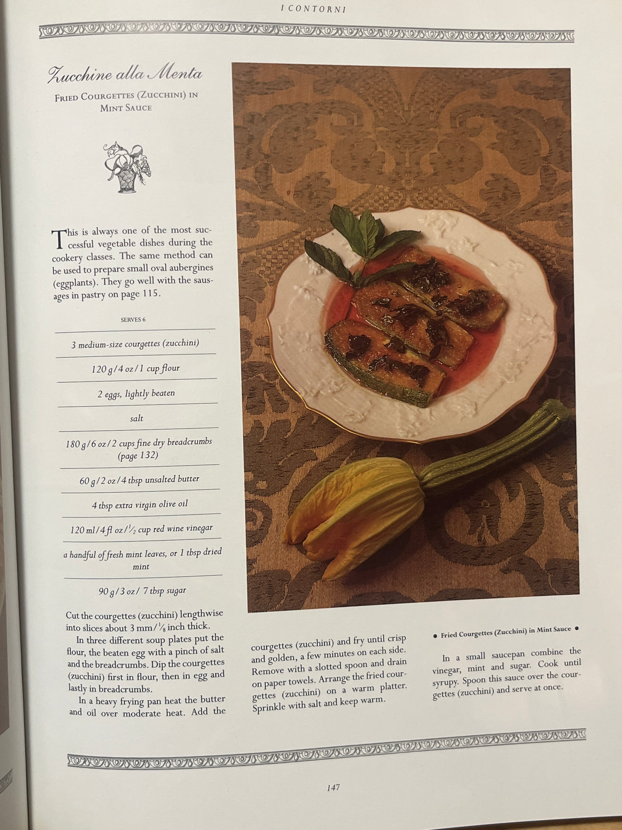The Villa Table cookbook page featuring Zucchine alla Menta, showcasing fried zucchini in mint sauce with the printed recipe and a zucchini blossom garnish.