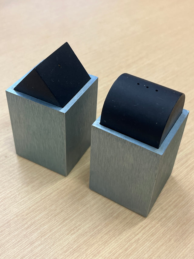 Elika anodized aluminum salt and pepper shakers by David Tisdale, featuring a geometric 1980s Memphis-style design on a wooden table.