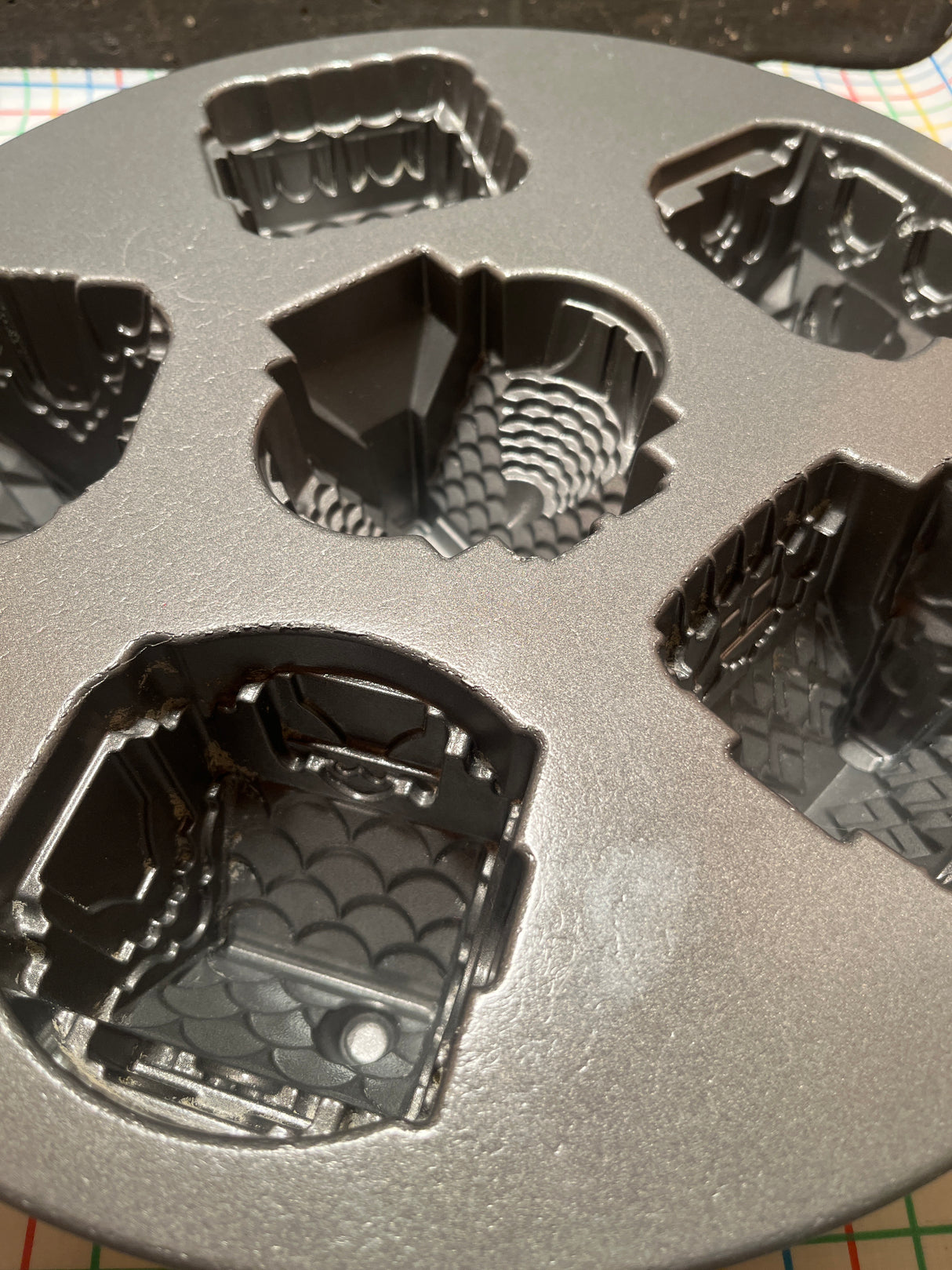 Cozy Village cast aluminum baking pan mold by Nordicware, featuring six decorative cavities for intricate mini-cakes, with nonstick surface ensuring easy release and uniform baking.