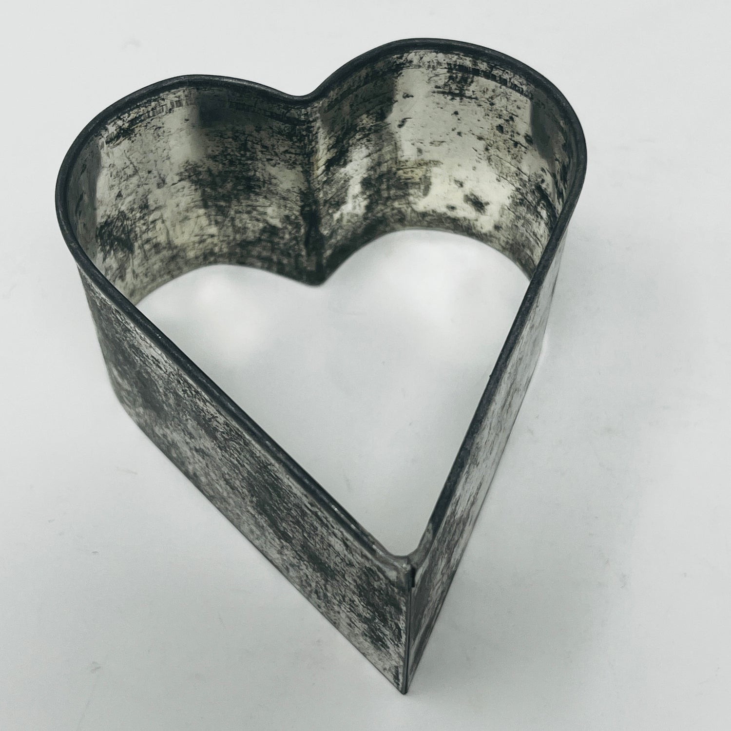 Mid-century metal heart-shaped cookie cutter, featuring a large, adaptive handle for easy gripping, part of a collection including vintage and celestial shapes.