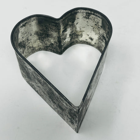 Mid-century metal heart-shaped cookie cutter, featuring a large, adaptive handle for easy gripping, part of a collection including vintage and celestial shapes.