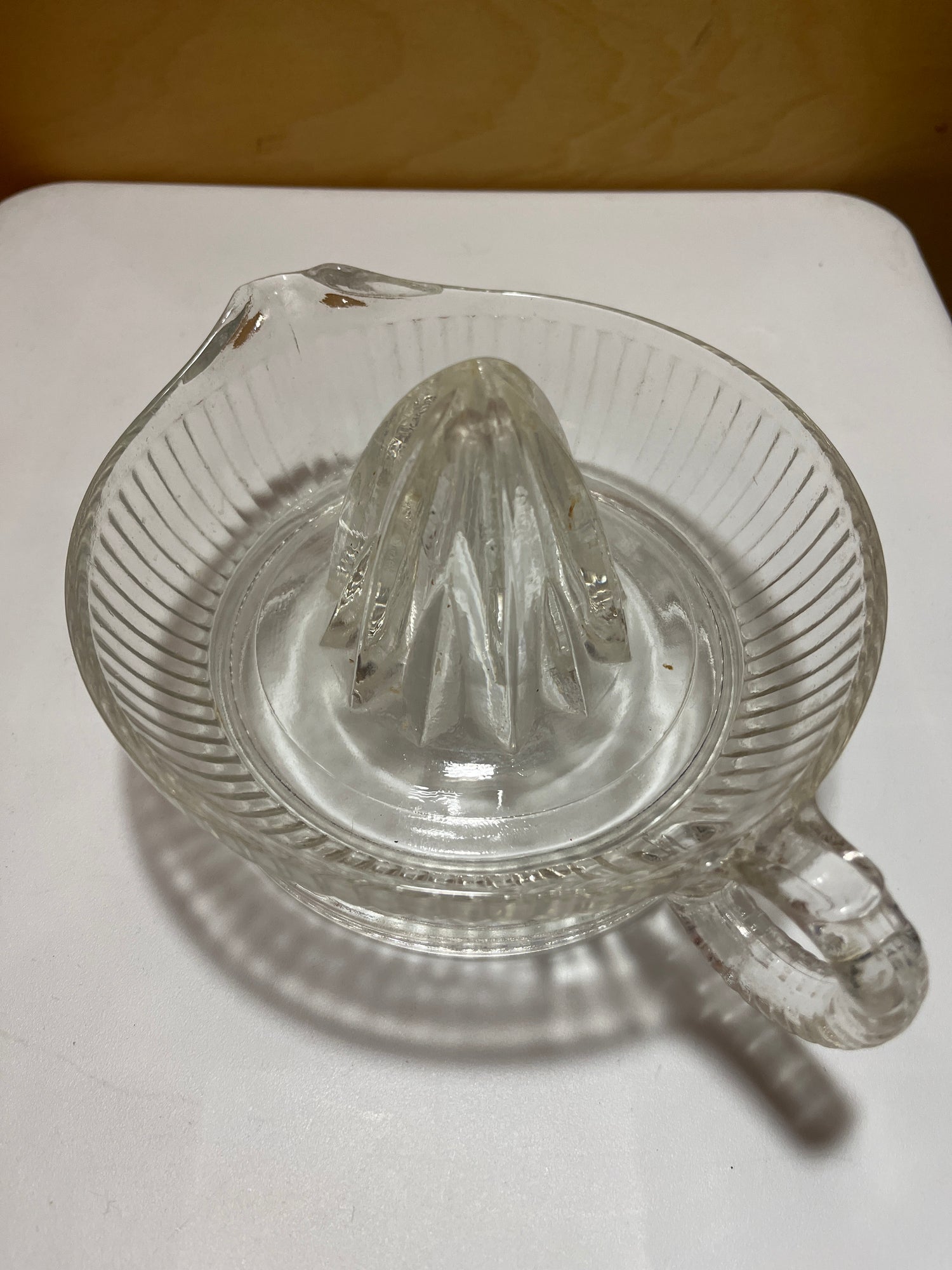 Vintage glass citrus juicer with spout, handle, and deep sides, designed to hold one cup of liquid. No visible chips or scratches.