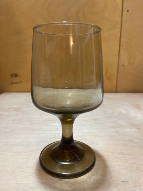 Libbey Tawny accent wine glass with a smokey hue, featuring a thick stem and flared base, showcased empty on a wooden surface.