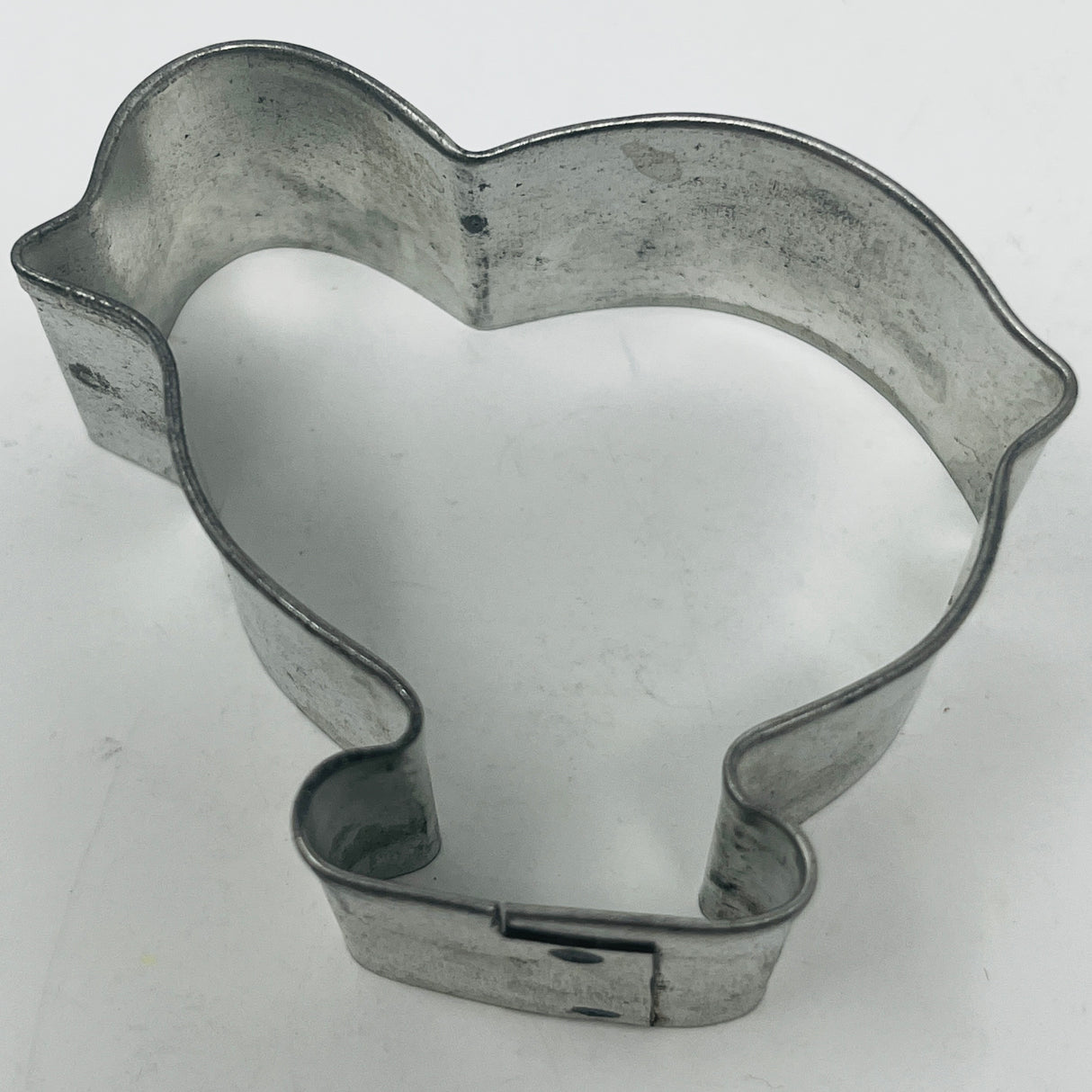 Mid-century metal cookie cutter on a white surface, featuring an adaptive design with a large handle for easy grip, inspired by 1930s styles.
