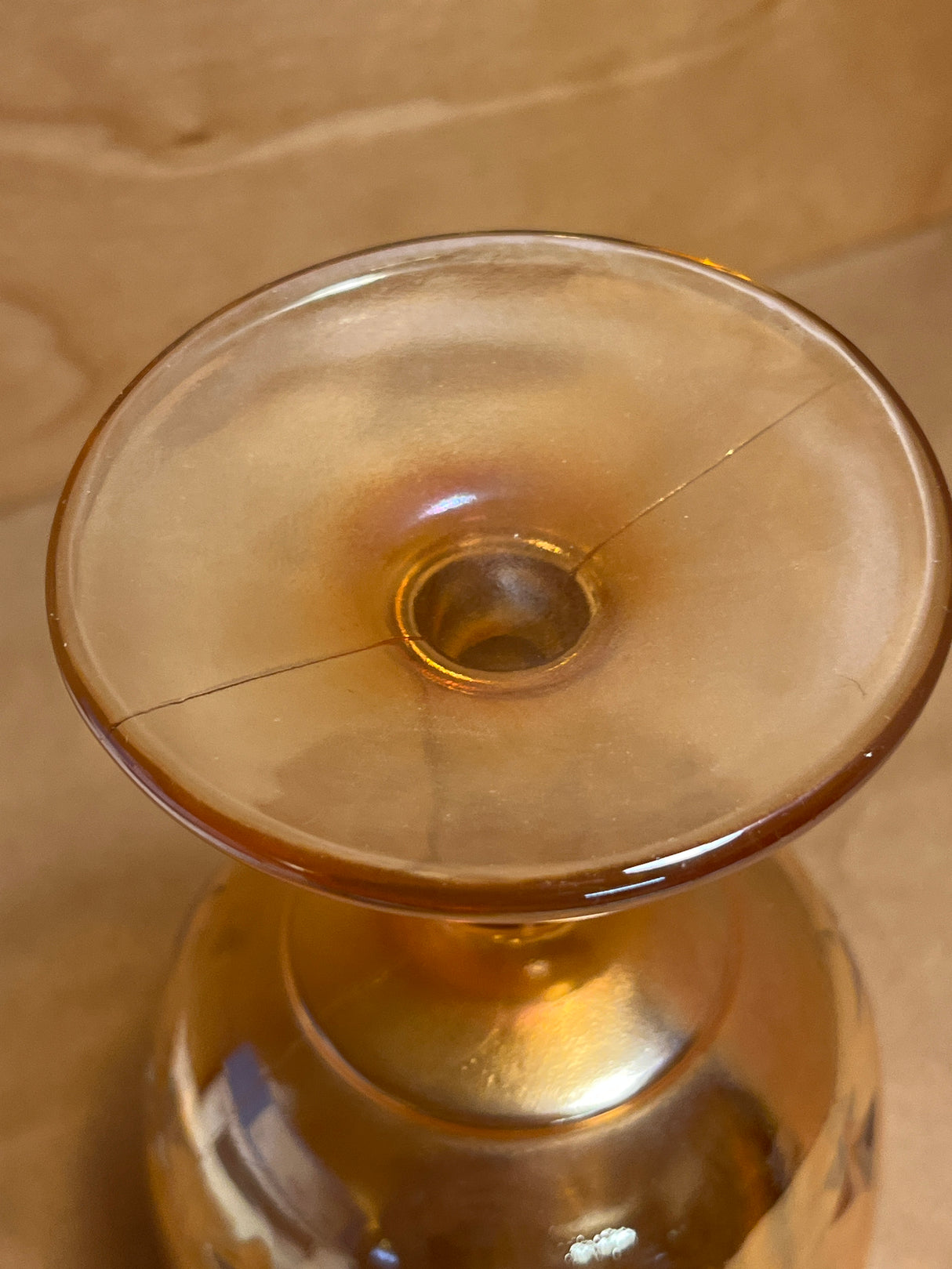 Bartlett Collins Star Marigold Carnival orange glass goblet, viewed from above, showcasing its flared, saucer-shaped top with a central hole and a fine crack extending outward.