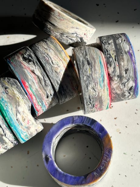 Napkin rings from Reimagined Recycling: Chunky, cylindrical rings with marbled striations, showcasing a unique, lightweight design, crafted from multi-layered recycled materials. Each set is distinct.