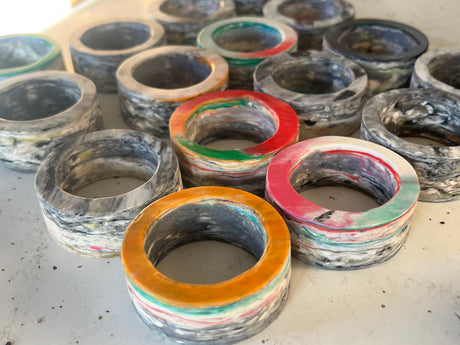 Napkin rings from Reimagined Recycling: Chunky, marbled resin rings with unique colored bands, designed to hold napkins securely. Each set is distinct with varied patterns.