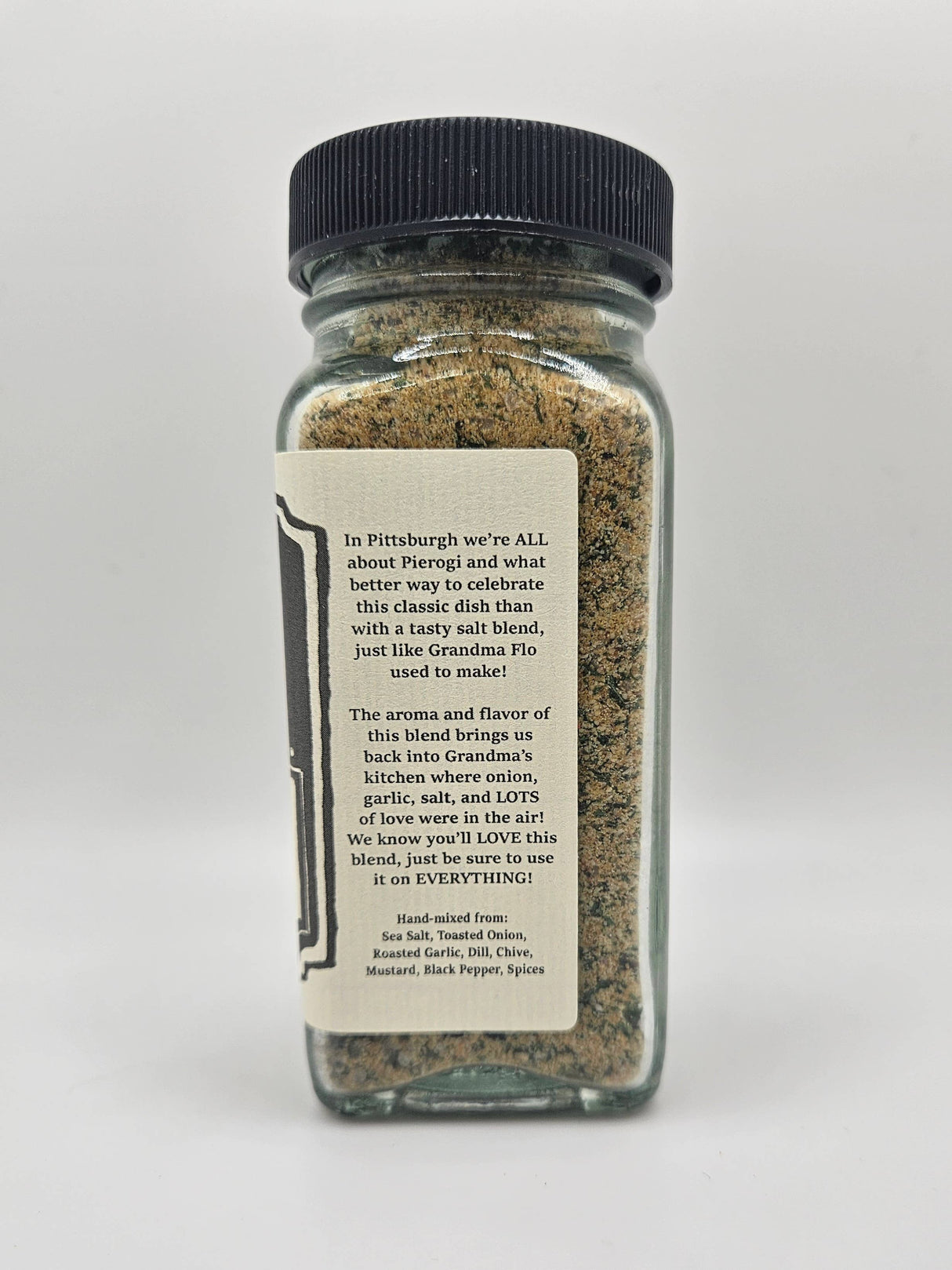 NEW Pierogi Salt! A small glass jar with a black lid contains Grandma Flo's hand-mixed spice blend for enhancing pierogi and other dishes.