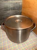 Large stainless steel stockpot with lid and handles on grid cloth, ideal for high-volume cooking. Made in USA, NSF-Certified for professional kitchens.