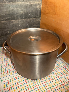 Large stainless steel stockpot with lid and handles on grid cloth, ideal for high-volume cooking. Made in USA, NSF-Certified for professional kitchens.