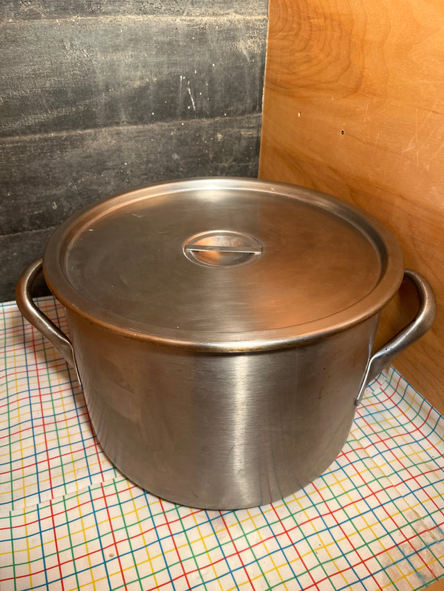 Large stainless steel stockpot with lid and handles on grid cloth, ideal for high-volume cooking. Made in USA, NSF-Certified for professional kitchens.