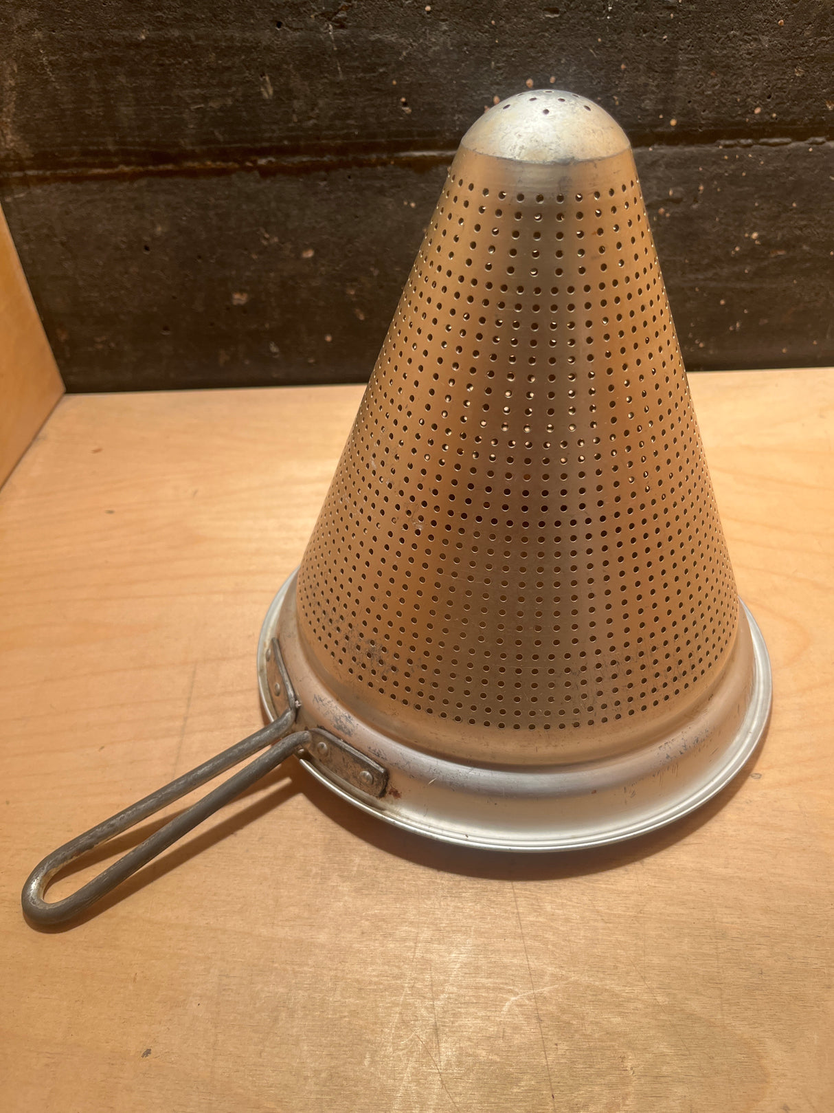 Cone strainer: A metal, cone-shaped kitchen tool with small holes, ideal for finely straining soups, sauces, and stocks by separating liquids from solids.