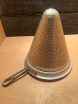 Cone strainer: A metal, cone-shaped kitchen tool with small holes, ideal for finely straining soups, sauces, and stocks by separating liquids from solids.