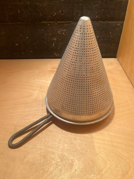 Tiny pointy cone sieve strainer - aluminum, featuring a perforated design for efficient straining. Secure handle and minor dent at cone tip noted. Ideal for large batch preparation.