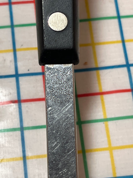 Slotted serving spoon - stainless steel with Bakelite handle by EKCO Forge, features a perforated bowl for draining, shown with their logo on the handle.