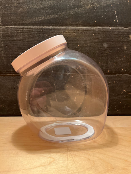 OXO POP medium food storage jar 3 qt., clear plastic with pale-pink lid, rests on its side, showcasing its easy-open design and spacious, accessible opening.