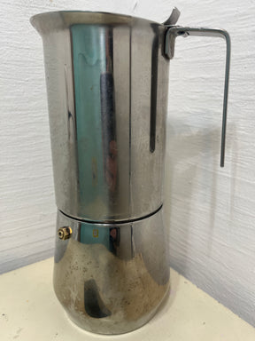 Ilsa Turbo Express 6-Cup 18/10 stainless steel stovetop espresso pot on countertop, showcasing its sleek design and noted tarnishing around the base.