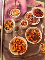 Martha Stewart’s Agora D’oeuvres spread showcasing assorted seasoned nuts in bowls, including coconut-curry macadamias, honey-roasted almonds, and spicy paprika cashews, with recipe pages noted.