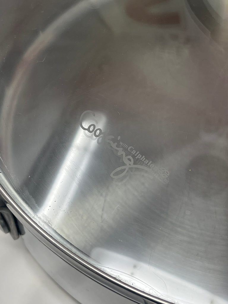 Calphalon 5003 3qt sauté pan with lid featuring a close-up of its logo and silver finish, highlighting silicone handles.