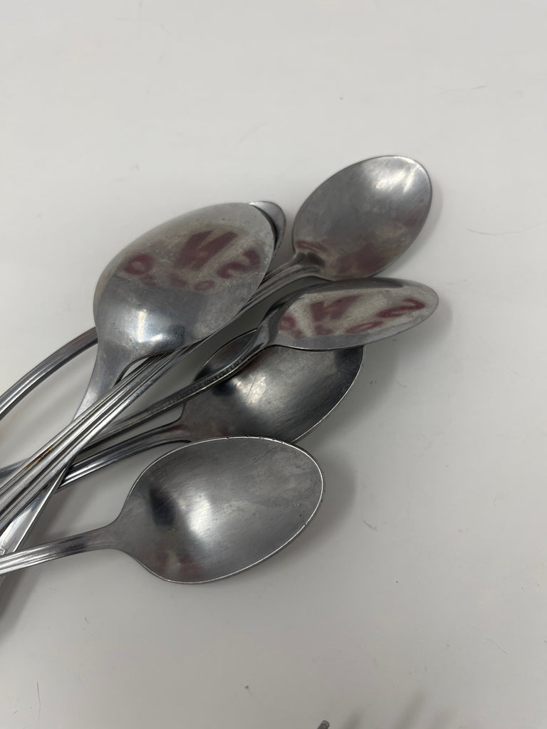 Basic metal cutlery, featuring a group of steel spoons on a white surface, part of a set including forks and knives available individually.