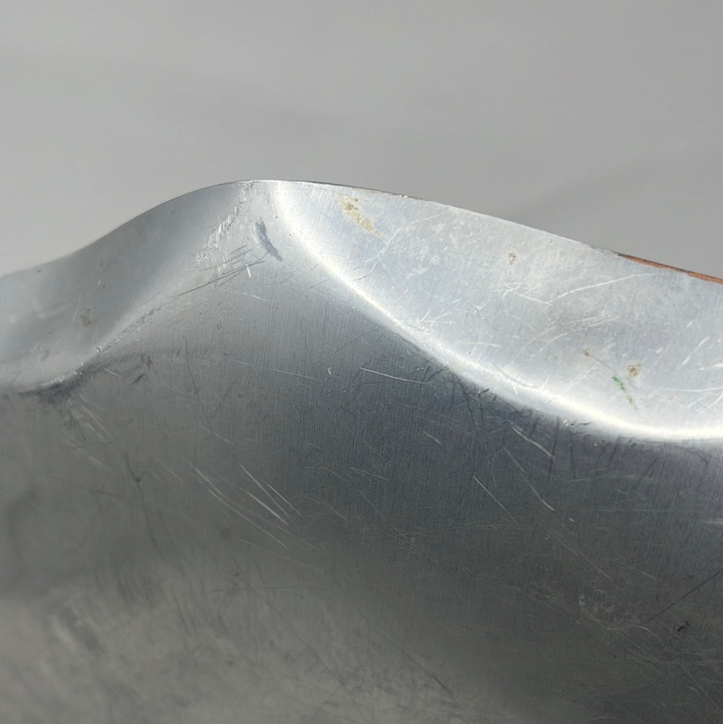 Close-up of metal serving tray with mallard duck design and scalloped edge, showcasing scratches and scuff marks. Mallard duo emerges from water, symbolizing resilience and elegance.