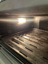 Close-up of a Breville oven featuring its grill and interior light, showcasing the appliance's sleek, steel design suitable for modern kitchens.