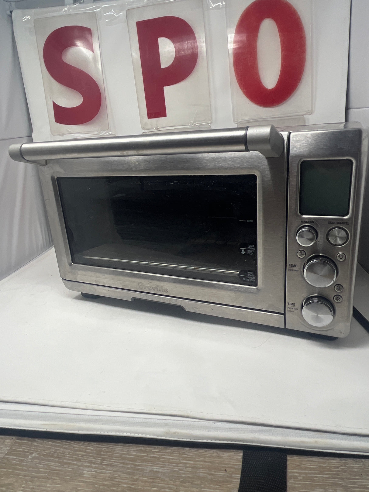 Breville oven on white surface, showcasing its sleek silver design and clear front window, highlighting its function as a versatile kitchen appliance.