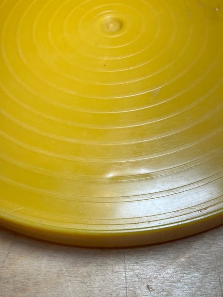 Close-up of the Bee Plastics harvest gold lazy Susan tray, showcasing its circular design with molded concentric rings, resembling an unbranded plastic flying disc.