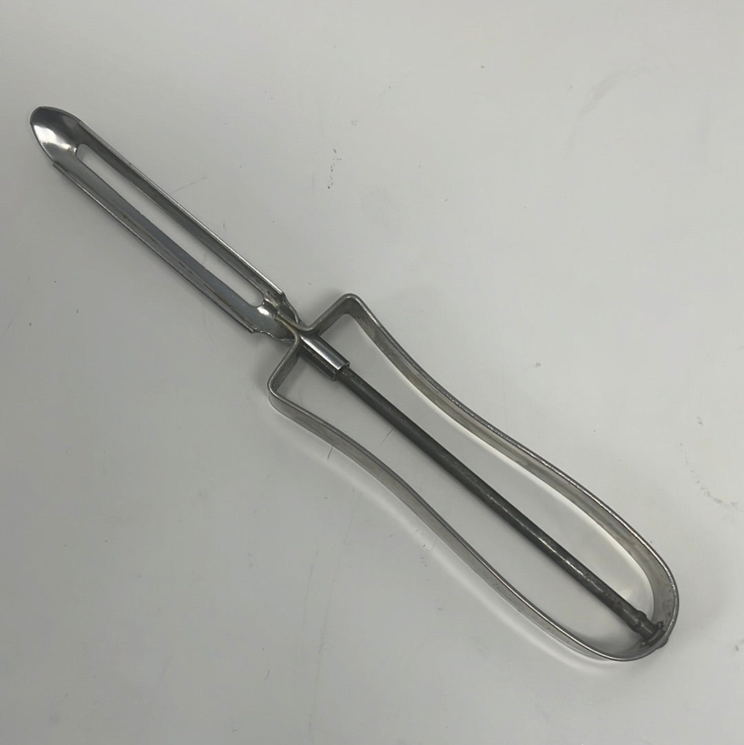 A sharp EKCO stainless steel vegetable peeler with floating blade, featuring a curved tip for precise cutting. Inscription: “NEE ACTION PAT. NO 2232940”.