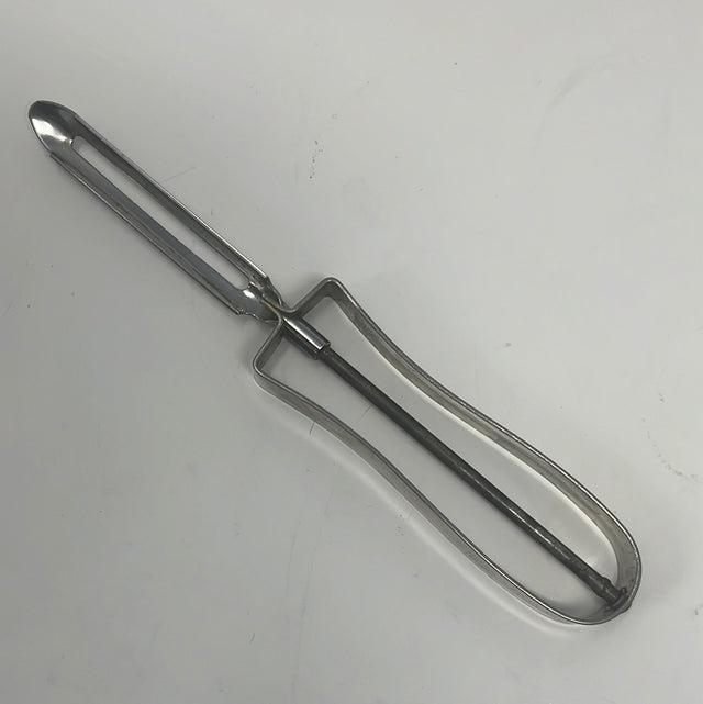 A sharp EKCO stainless steel vegetable peeler with floating blade, featuring a curved tip for precise cutting. Inscription: “NEE ACTION PAT. NO 2232940”.