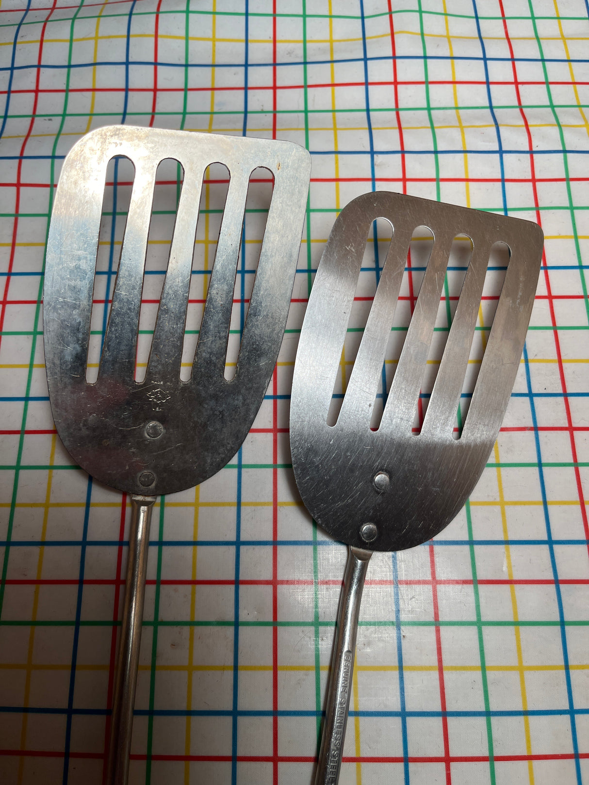 Flat thin steel slotted spatula with wood handle, featuring a broad, flat head with long slots, ideal for flipping and transferring hot foods.