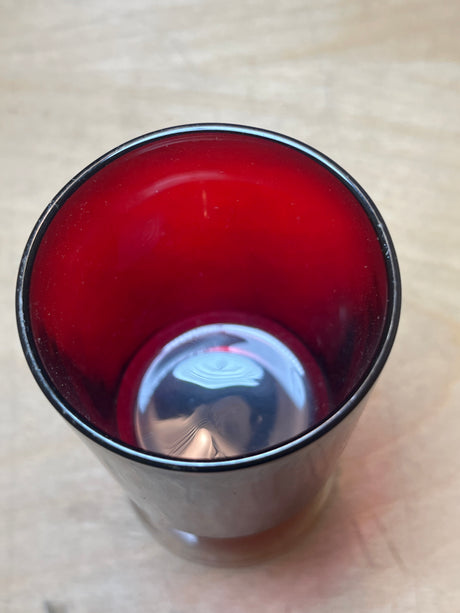 Luminarc/ARCOROC ruby red small wine glass, double-walled stainless-steel exterior, deep red interior, empty, reflecting light on a light wood surface.