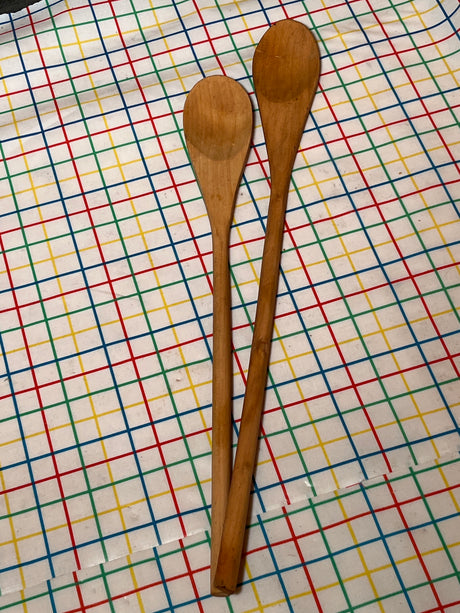Basic wooden spoon pair on a patterned cloth, showcasing long, flat designs ideal for non-stick cooking, with heat-resistant handles for safe, everyday use.